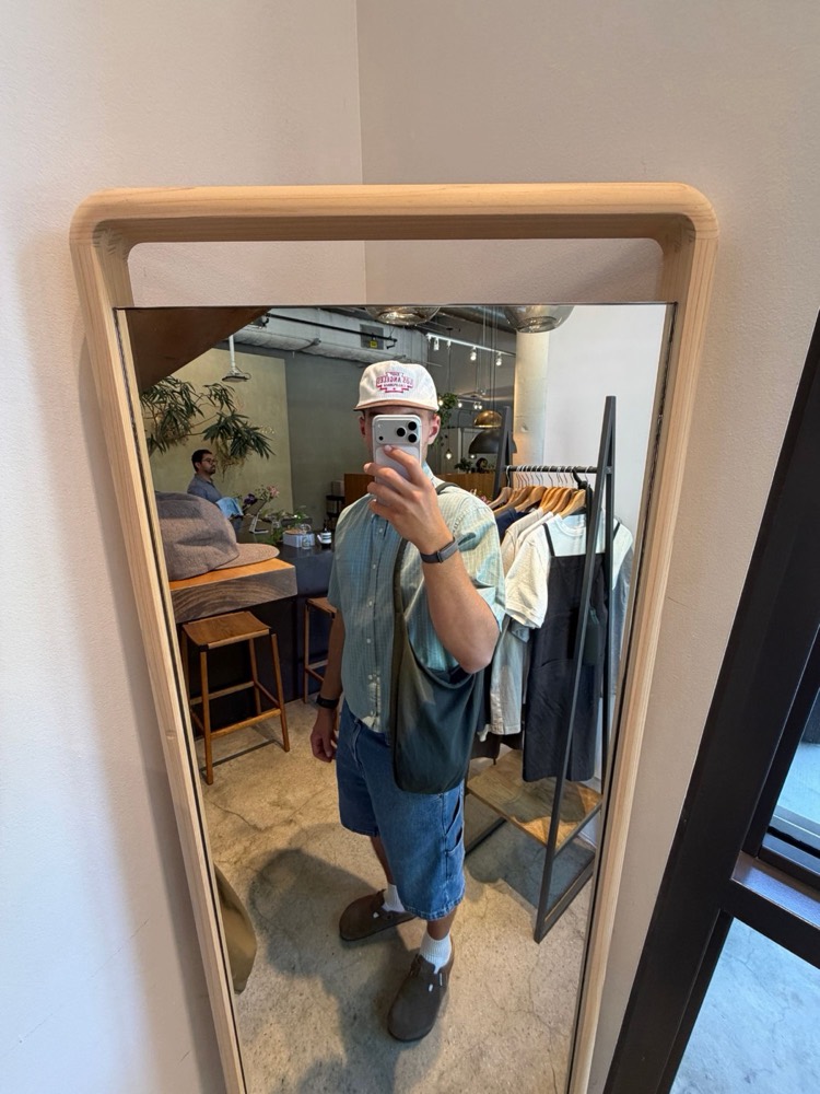 Mirror selfie of Jaxson in a shop, denim shorts and clogs
